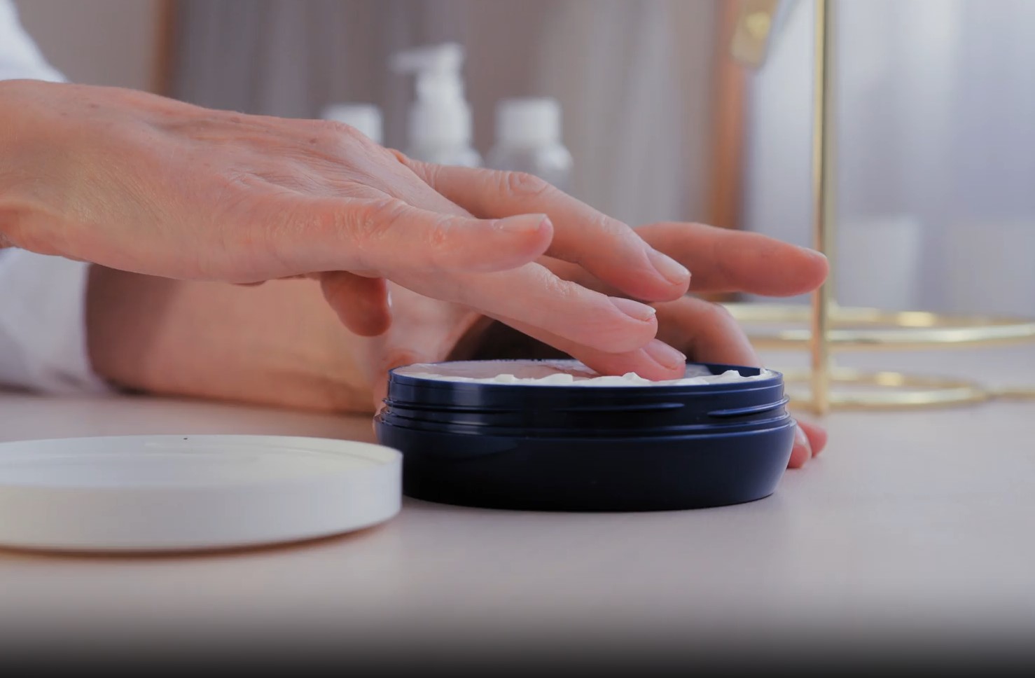 Hand reaching toward a cream on a table